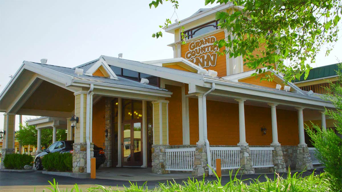 exterior of Grand Country Inn surrounded by greenery with car at entrance during day in Branson, Missouri, USA